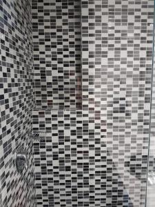um chuveiro com azulejos pretos e brancos na casa de banho em Aparta Suite La Candelaria em Bogotá