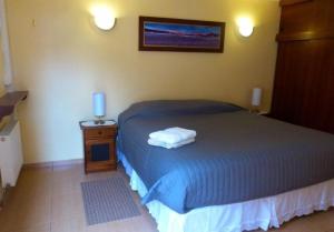 1 dormitorio con 1 cama y mesita de noche con toallas en Hostal Solor, en San Pedro de Atacama