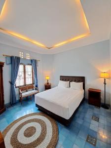 a bedroom with a large white bed and a rug at Kutus Kutus Clemmie Huis in Yogyakarta