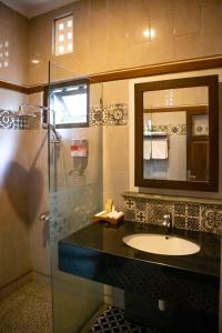 a bathroom with a sink and a mirror and a shower at Kutus Kutus Clemmie Huis in Yogyakarta
