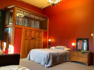a bedroom with orange walls and a bed and a mirror at The Ghost Lodge in Granity