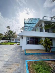 ein weißes Haus mit einem Innenhof davor in der Unterkunft Chameleon Beach Resort, Cherai in Kochi