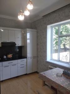 cocina con armarios blancos, mesa y ventana en Elchins villa, en Gabala