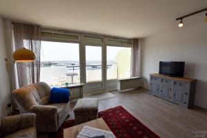 a living room with a large window and a television at Haus "Panorama" Appartement PAN105 in Duhnen