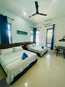 Dos camas en una habitación con almohadas azules. en NS Vacation Home Muar with Kids Friendly Pool en Muar