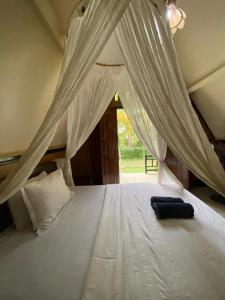 a bedroom with a bed with white mosquito netting at MATRAHAYA BUNGALOWS in Tetebatu