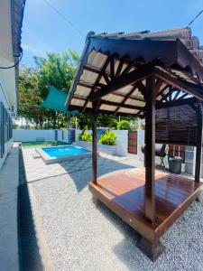 a wooden gazebo in a backyard with a pool at NS Vacation Home Muar with Kids Friendly Pool in Muar