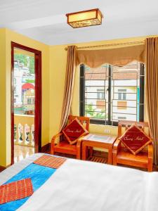 um quarto com uma cama, 2 cadeiras e uma janela em Cherry Hotel em Sapa