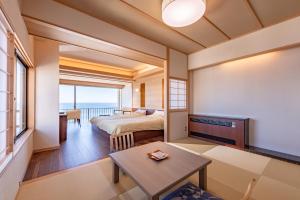 a bedroom with a bed and a table in a room at Inatori Tokai Hotel Yuen in Higashiizu