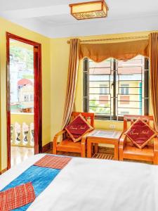 um quarto com uma cama e cadeiras e uma janela em Cherry Hotel em Sapa