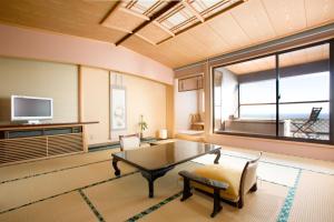 a living room with a table and a large window at Inatori Tokai Hotel Yuen in Higashiizu