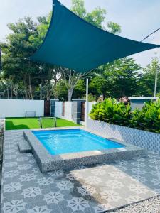 a swimming pool with a large umbrella over it at NS Vacation Home Muar with Kids Friendly Pool in Muar