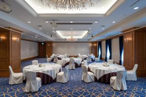 a banquet room with white tables and chairs and a chandelier at Hotel Nikko Princess Kyoto in Kyoto