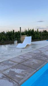 una silla blanca sentada en un patio junto a una piscina en Casa full equipada (villa seca) en Tunuyán