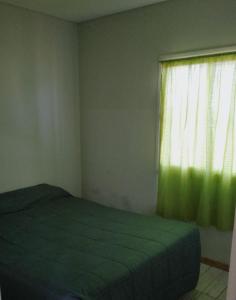 a bedroom with a green bed and a window at Casa con piscina in Maipú