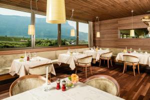 un restaurante con mesas y sillas blancas y ventanas en Hotel Girlanerhof, en Appiano sulla Strada del Vino