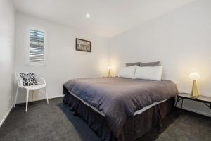 - une chambre avec un grand lit et une chaise dans l'établissement Ashgrove Lane, à Wanaka