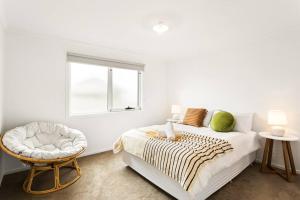 um quarto com uma cama com uma cadeira e uma janela em Cozy Beach Bungalow in Cowes em Cowes