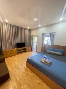um quarto com uma cama azul e uma televisão em THANH XUÂN HOMESTAY em Da Nang
