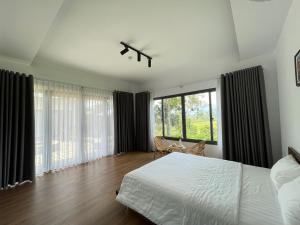 1 dormitorio con cama blanca y ventana grande en AN Homestay&coffee, en Di Linh