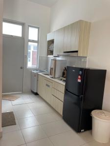a kitchen with a black refrigerator and cabinets at NEW Desaru pengerang sebana cove 15pax RAPID MINI ZOO in Pengerang +4 photos