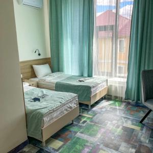 a room with two beds and a window at Scandi Hotel in Uralsk