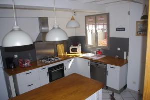 uma cozinha com armários brancos e um forno com placa de fogão em Gite la tuilerie em Thuir