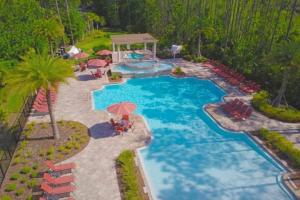 - une vue sur la piscine avec des chaises et un parasol dans l'établissement Fountains Retreat condo, à Kissimmee