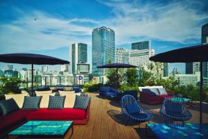 a rooftop patio with chairs and umbrellas and a city skyline at Hotel Indigo Tokyo Shibuya in Tokyo