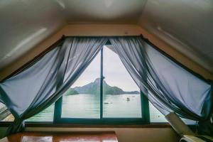 een raam in een boot met uitzicht op het water bij Bangka Hostels in El Nido