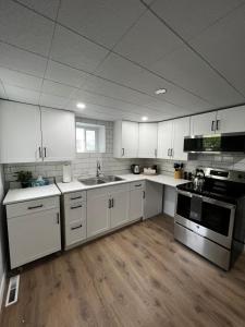 a kitchen with white cabinets and stainless steel appliances at Cozy Home- Winnipeg Airport, Downtown and Polo Park in Winnipeg