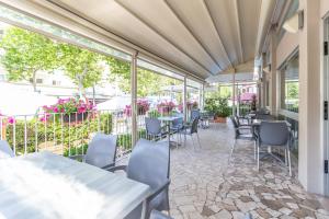 a patio with tables and chairs and windows at Hotel Haway in Rimini