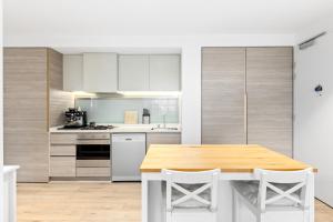 cocina con mesa de madera y armarios blancos en Contemporary Comfort, en Melbourne