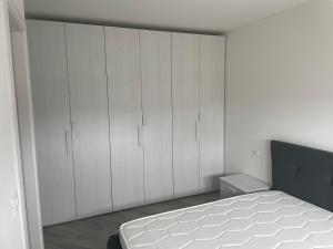 1 dormitorio con armarios blancos y 1 cama blanca en Appartamento in Villa Gioiosa, en Grado