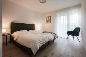 1 dormitorio con 1 cama grande y 1 silla en Astor Apartments, en Valdaora