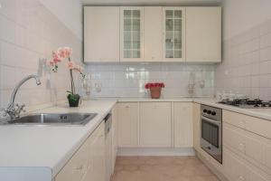 eine weiße Küche mit weißen Schränken und einem Waschbecken in der Unterkunft Charming House con Giardino - 10' da Cagliari e Poetto in Quartu SantʼElena