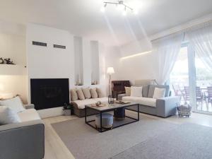 a living room with white furniture and a fireplace at Varkiza Sea View Apartment - Free Parking in Vari