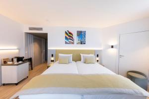a bedroom with a large white bed and a desk at Crowne Plaza - Marseille Le Dôme in Marseille