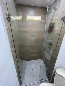 y baño con ducha de cristal y aseo. en Hotel De León Estadio en Medellín