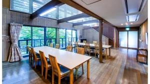 uma sala de jantar com mesas, cadeiras e janelas em 但馬長寿の郷　宿泊棟「夢」ロッジ em Yabu