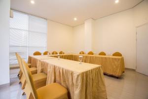 Best Inn Balikpapan في باليكبابان: قاعة اجتماعات مع طاولتين وكراسي ونافذة