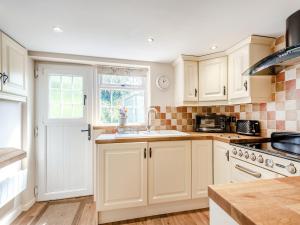 una cocina con armarios blancos y fregadero en Townhead Cottage, en Newbiggin