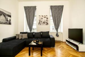 uma sala de estar com um sofá preto e uma televisão em Raimond Apartment em Viena