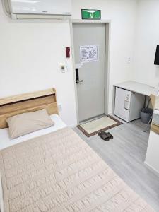 Jest to biały pokój z łóżkiem i biurkiem. w obiekcie BoA Travel House w Seulu