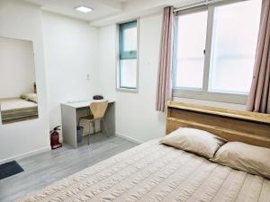 a bedroom with a bed and a desk and windows at BoA Travel House in Seoul