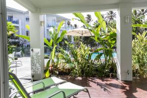 a patio with chairs and an umbrella and plants at Beaches Holiday Apartments - Official Onsite Reception & Check In in Port Douglas