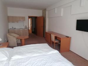 a bedroom with a bed and a desk and a kitchen at Hotel Kaskáda in Bojnice