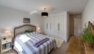 a bedroom with a large bed with a striped blanket at Mariners Moon in Camber
