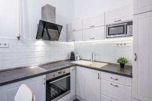 Una cocina blanca con fregadero y microondas. en Luxurious Apartments At City Center, en Budapest