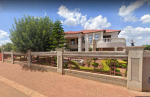 a large house with a fence in front of it at Kingdoms Place Guesthouse in Ga-Luka